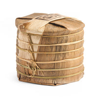 A tong of Dragon Tail sheng puerh cakes wrapped in bamboo bark