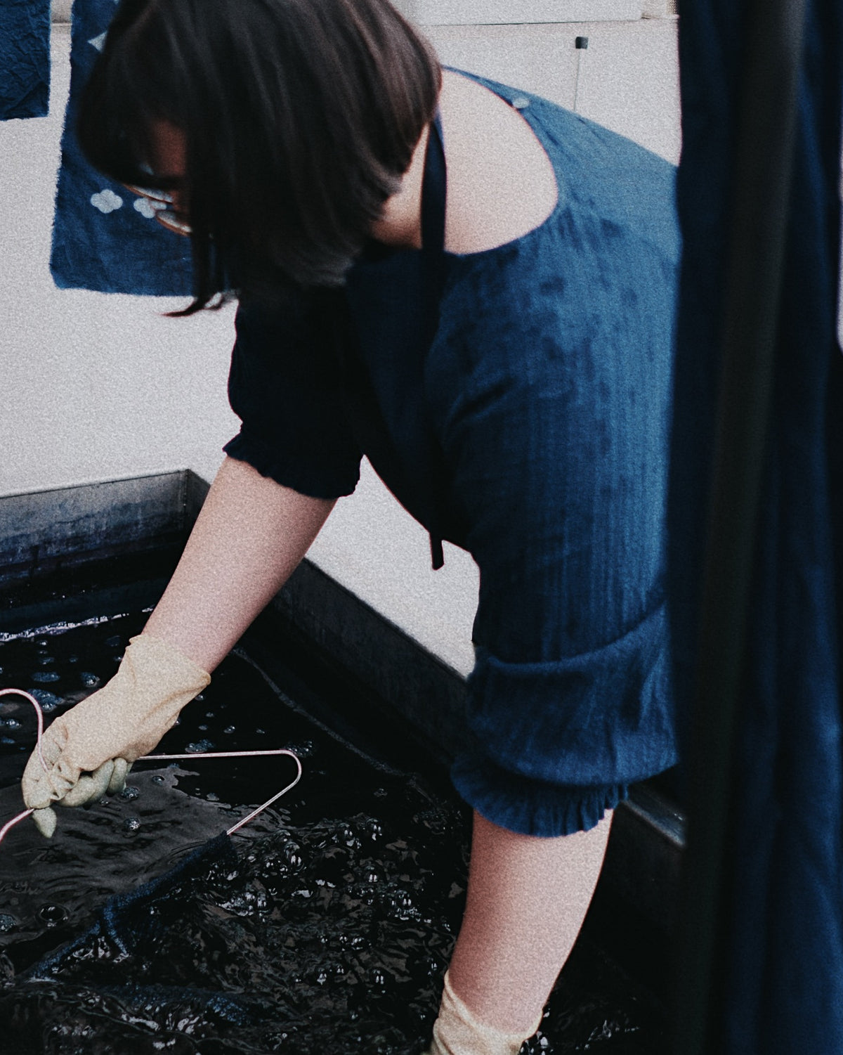 Jieyu Jiang lowering cloth into the indigo vat