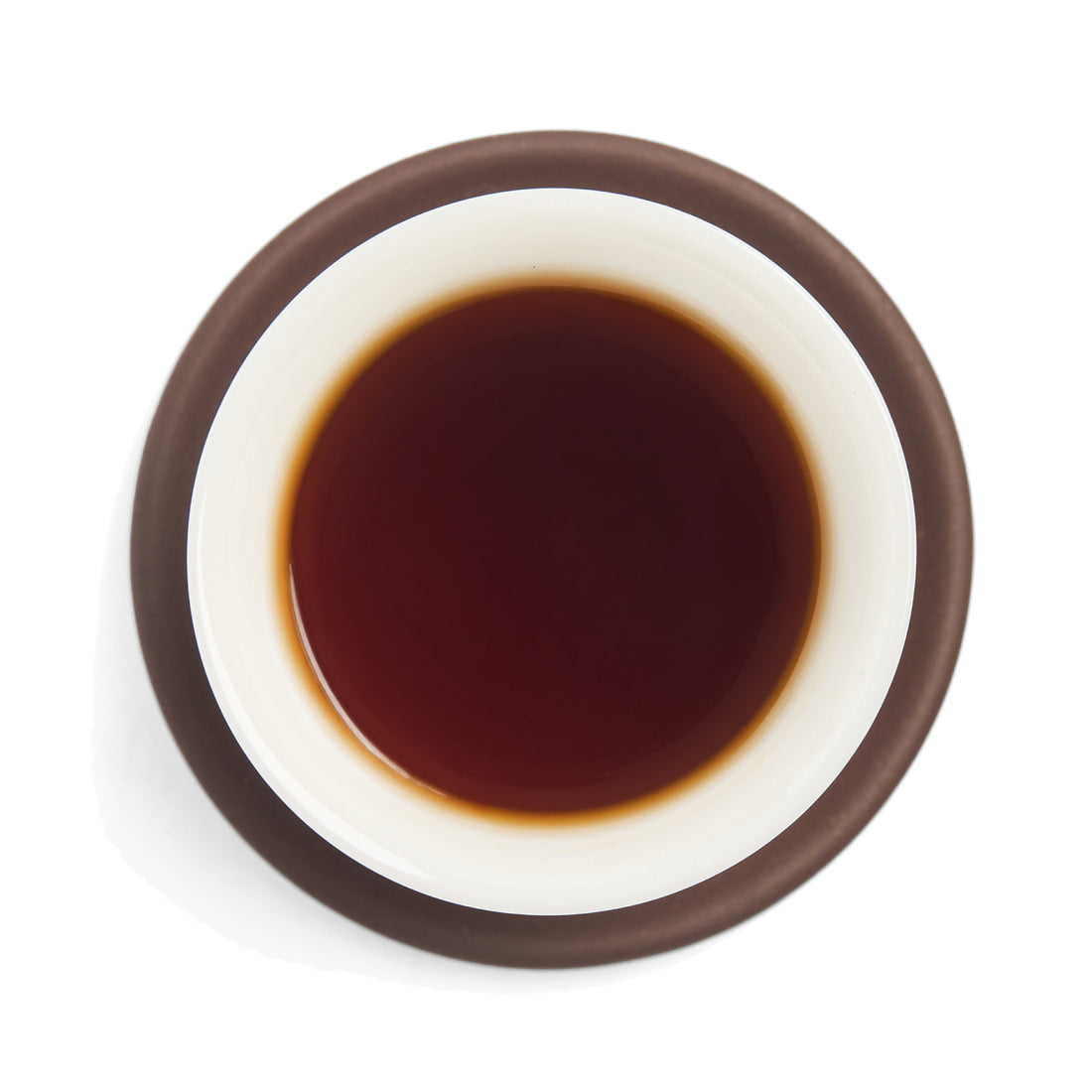 Brewed dark black tea (heicha) liquor in a white porcelain cup on a clay coaster, seen from above